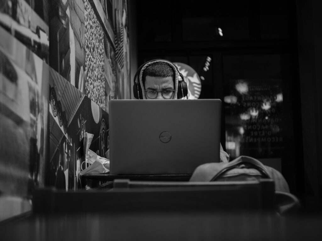 the best digital marketing freelancer working on a laptop with headphones in a café, focused on creating effective online marketing strategies.